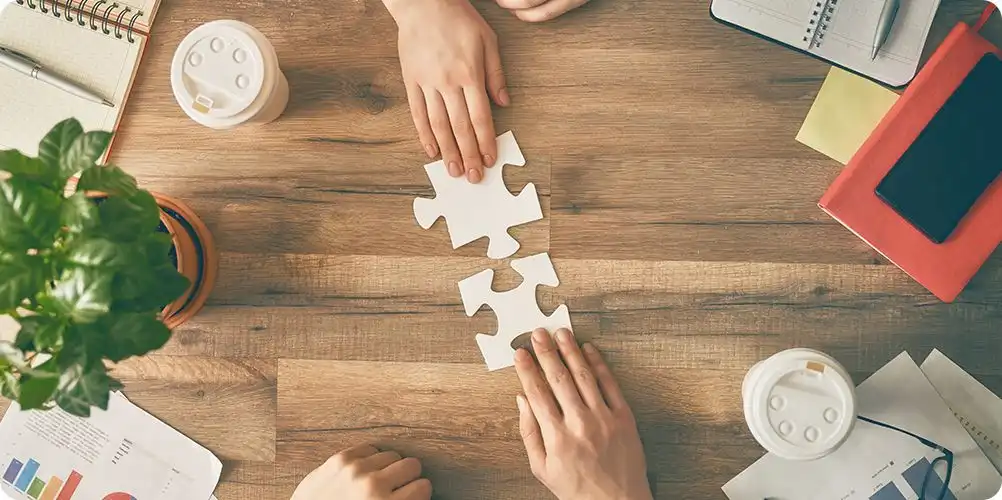 Joint ventures image depicting corporate leaders exchanging documents and smiling in a formal meeting room.