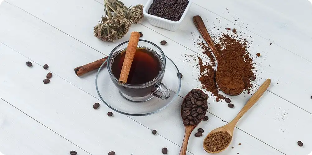 A close-up image of coffee beans or tea leaves alongside a dark, concentrated liquid extract.