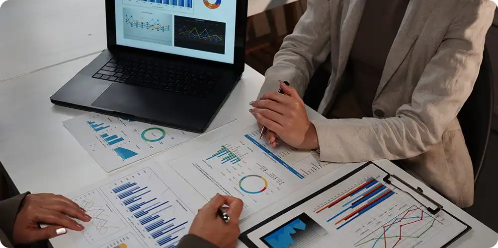 Market analysis and forecasts banner with financial charts, graphs, and business people discussing data in a boardroom.