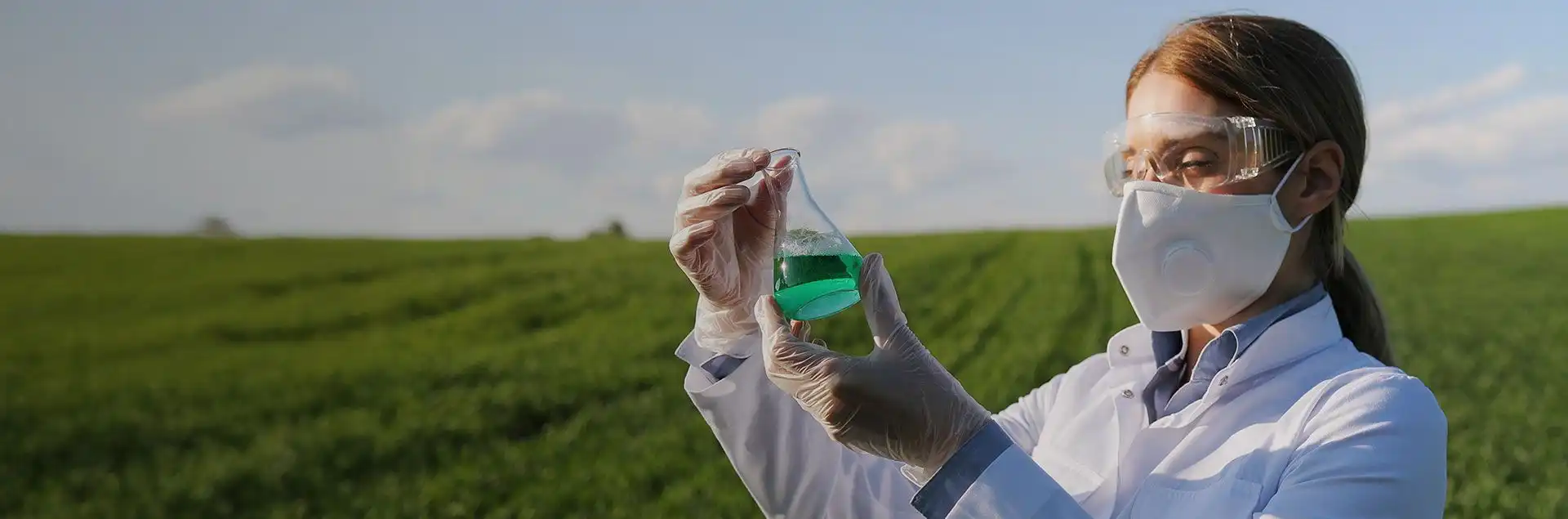 Woman dressed in medical attire holding a clear substance in her hands, representing healthcare or scientific research.