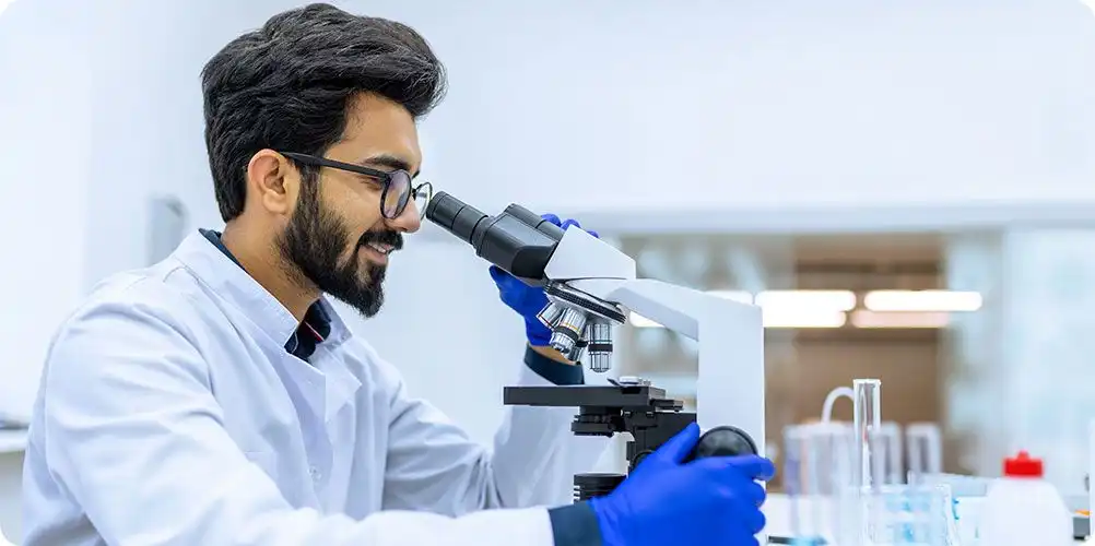 Man using a microscope symbolizing research positions and scientific investigation.