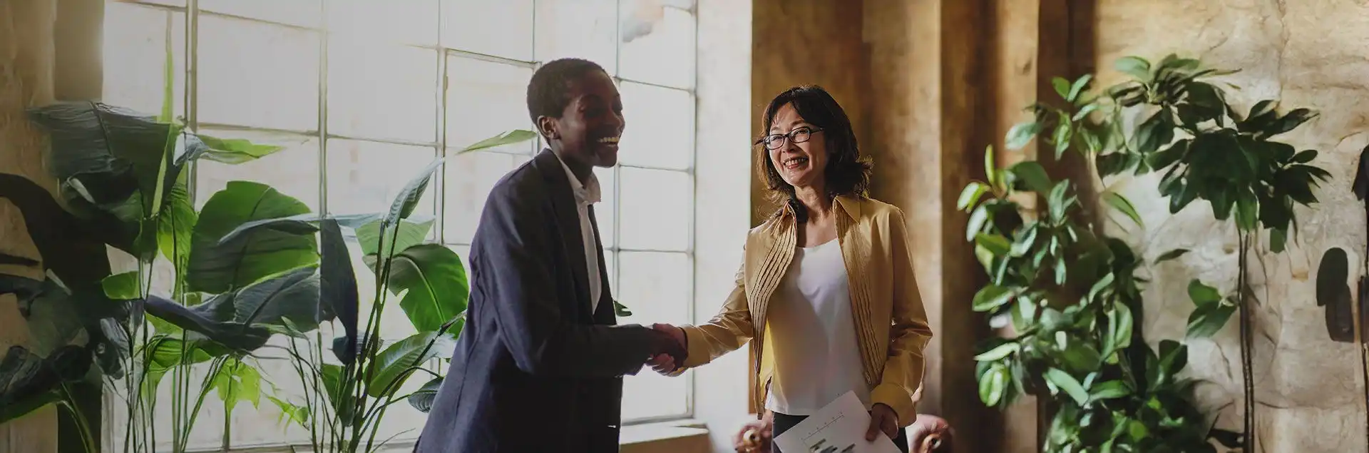 Partnership opportunities banner showing two business professionals shaking hands in an office setting with a city skyline in the background.